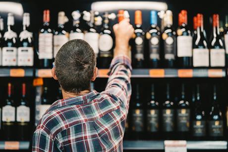 Man choosing bottle of tine in supermarket