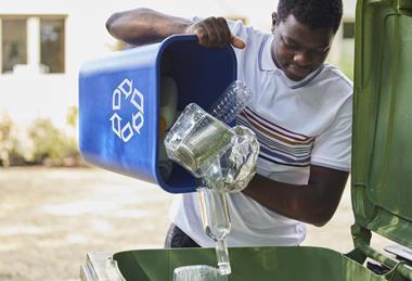 Man Emptying Household Recycling Into Green Bin Getty